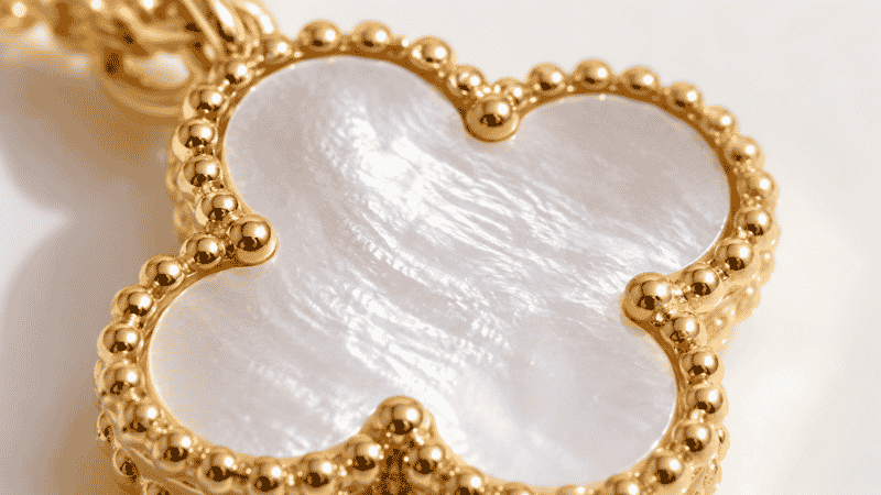 close-up detail of four-leaf clover pendant with mother-of-pearl inlay and gold beaded edge — Van Cleef inspired