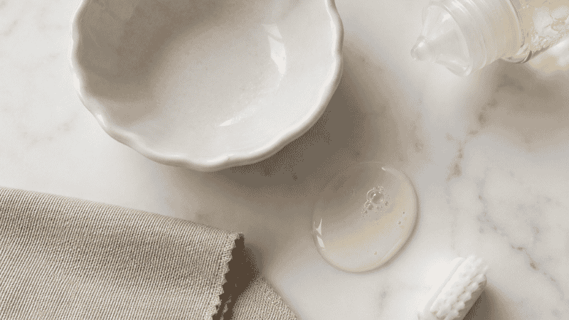 supplies needed to clean gold jewelry at home — bowl, dish soap, soft toothbrush, microfiber cloth