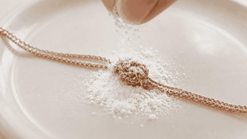 baby powder method to untangle a necklace — sprinkling baby powder on a knotted gold chain to reduce friction
