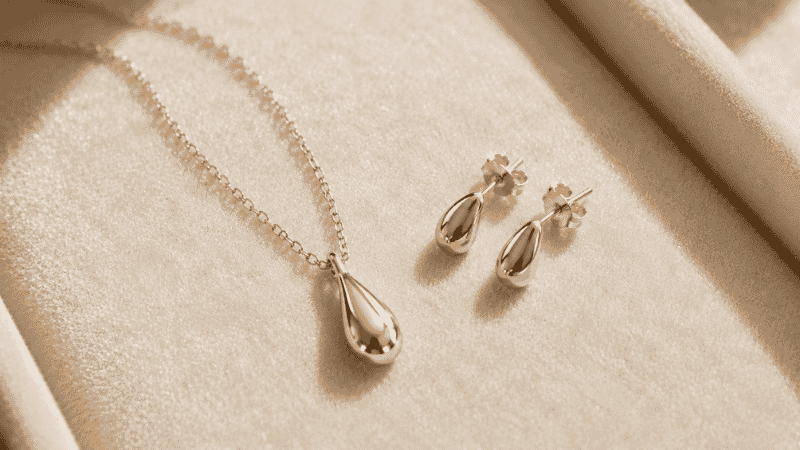 how to keep jewelry from tarnishing — polished gold necklace and earrings on cream velvet surface