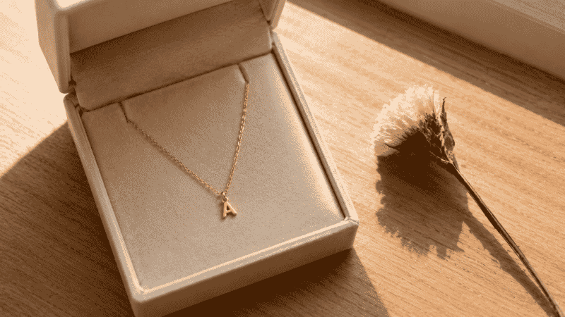 dainty jewelry as a gift — delicate gold initial necklace in cream velvet gift box with dried flower, thoughtful birthday present