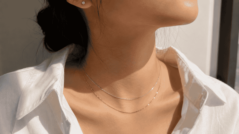 mixing gold and silver jewelry styling — gold and silver layered necklaces worn together with white shirt