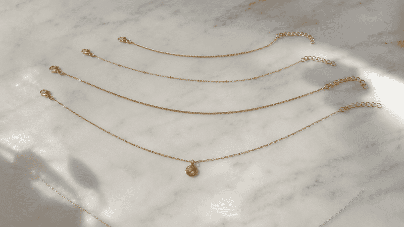necklace length guide for different necklines — four gold chains at 14 16 18 and 22 inches showing length comparison
