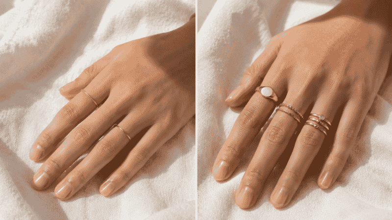 how to wear rings — three delicate gold rings on index middle and ring fingers resting on white linen