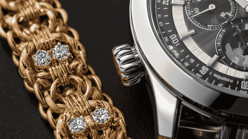 A high-detail macro shot demonstrating the "Rule of Two" by pairing a gold Van Cleef Alhambra bracelet with a masculine high-shine silver timepiece, illustrating the 2026 mixed-metal jewelry trend