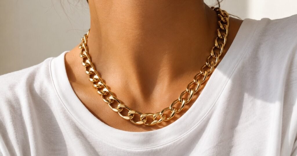 how to wear statement jewelry — chunky gold chain necklace worn with plain white t-shirt showing bold jewelry with simple outfit